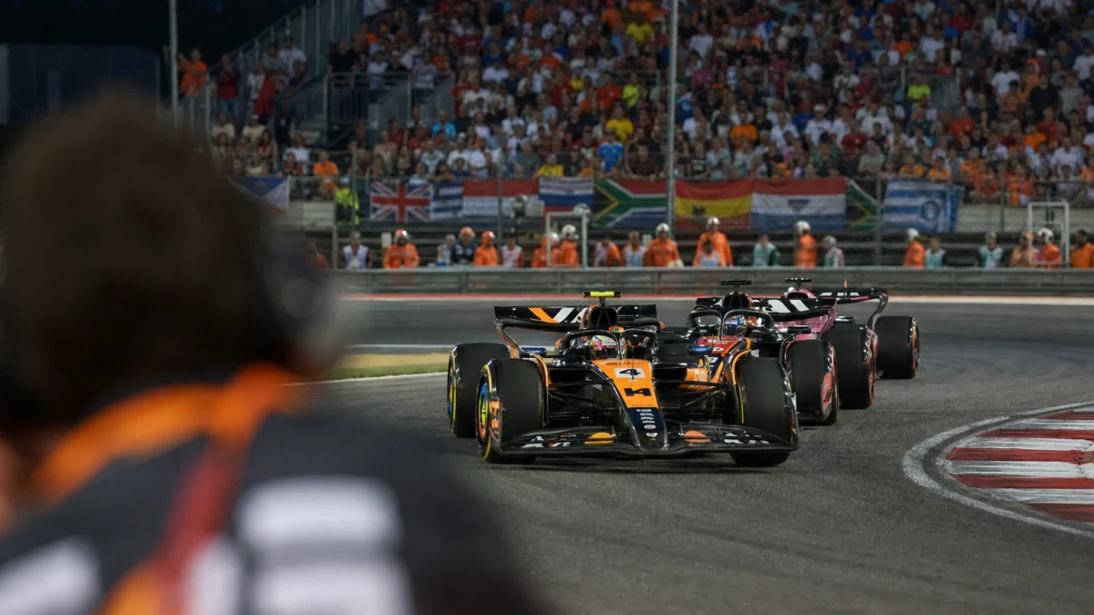 Röd formel 1-bil rullar ut ur depån under en morgonträning på en solig racerbana.