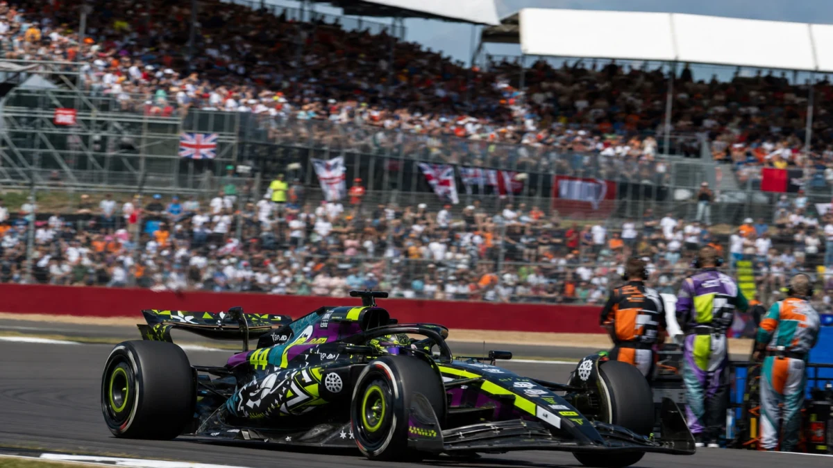 Röd formel 1-bil på väg ut ur en snabb kurva på Silverstone i eftermiddagsljus.